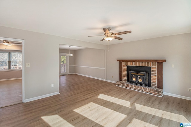 unfurnished living room with a wealth of natural light, wood finished floors, a ceiling fan, and baseboards