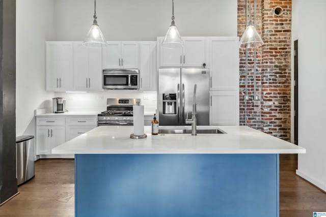 kitchen with hanging light fixtures, a center island with sink, stainless steel appliances, and light countertops