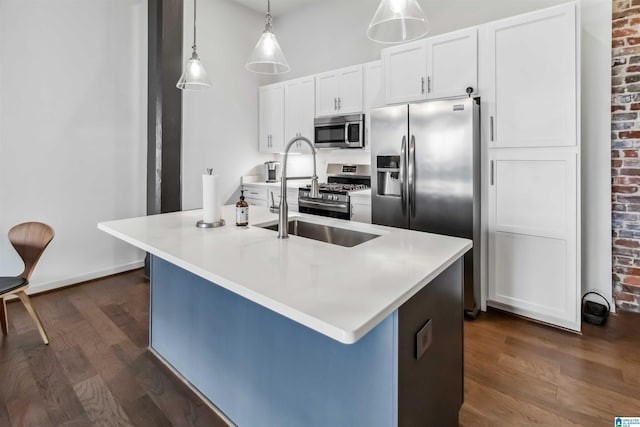 kitchen featuring a center island with sink, stainless steel appliances, light countertops, white cabinetry, and a sink