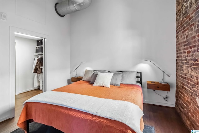 bedroom with brick wall and wood finished floors