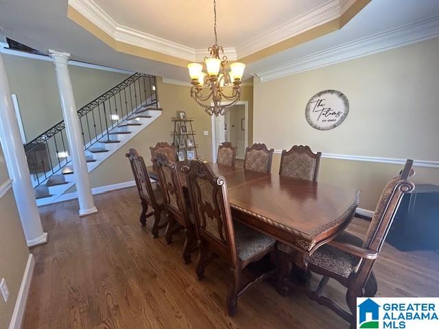 dining area with a raised ceiling, stairway, ornamental molding, wood finished floors, and ornate columns