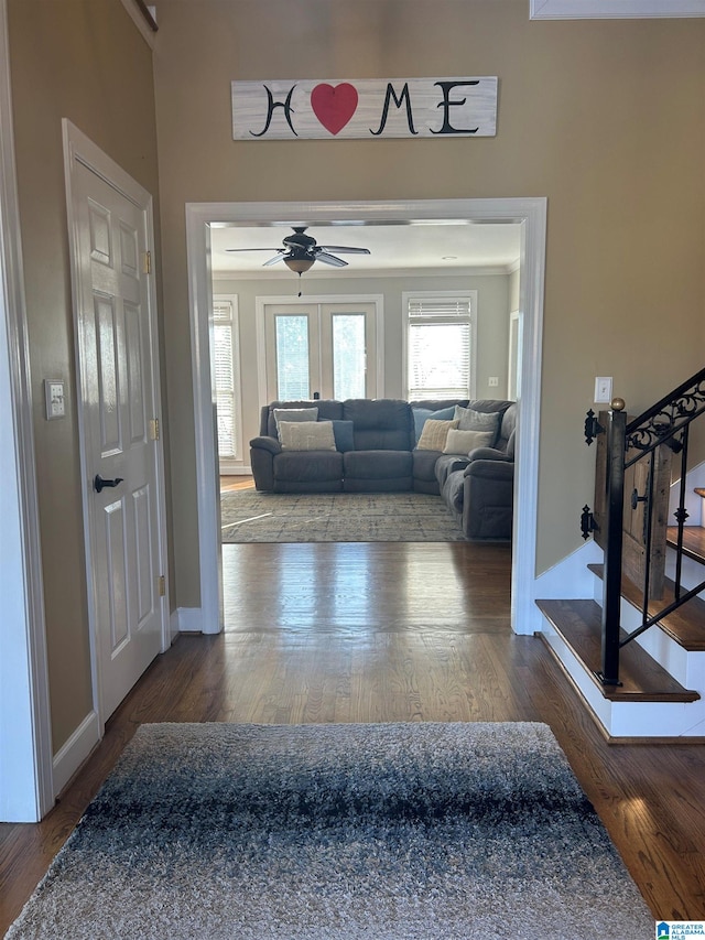 foyer featuring baseboards, ceiling fan, wood finished floors, stairs, and french doors