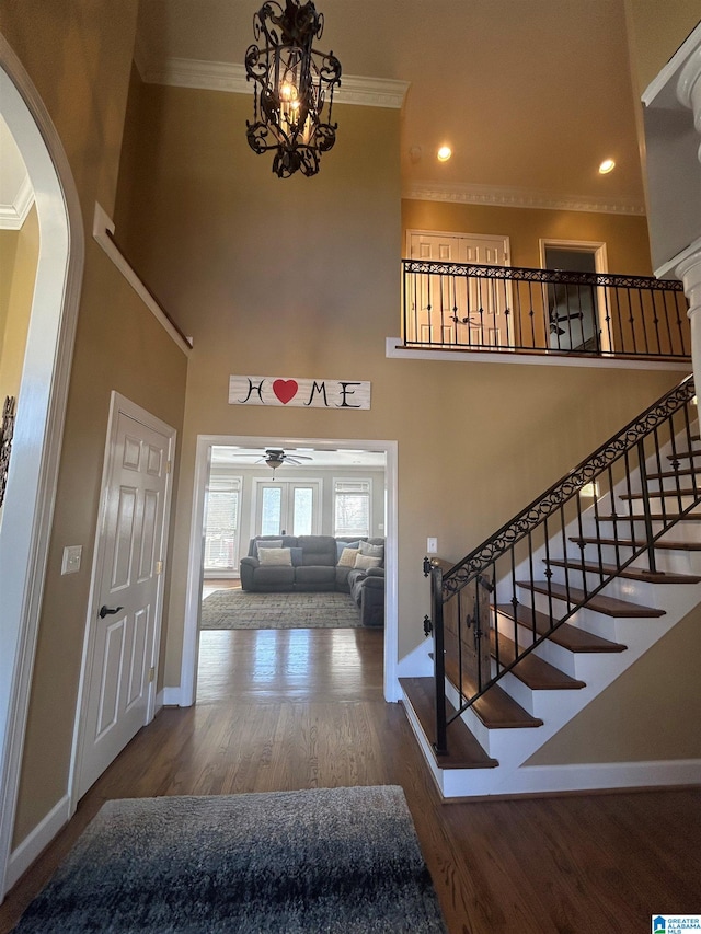 foyer featuring a towering ceiling, baseboards, ornamental molding, and wood finished floors