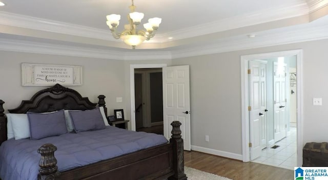 bedroom featuring wood finished floors, baseboards, ornamental molding, a raised ceiling, and an inviting chandelier