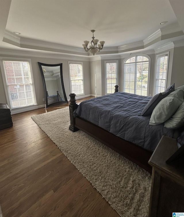 bedroom with a notable chandelier, a tray ceiling, wood finished floors, and ornamental molding