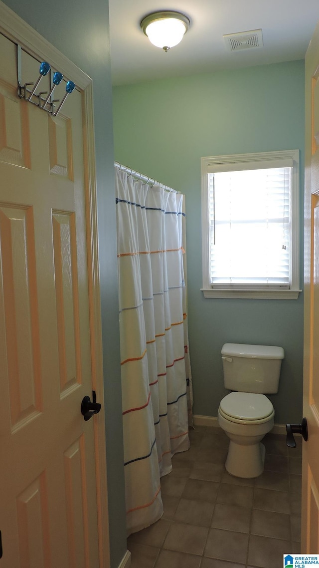 bathroom with curtained shower, tile patterned flooring, toilet, visible vents, and baseboards