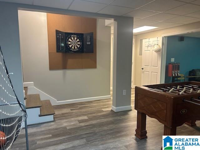 rec room featuring a paneled ceiling, baseboards, and wood finished floors