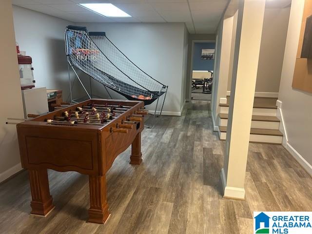 rec room with a drop ceiling, baseboards, and wood finished floors