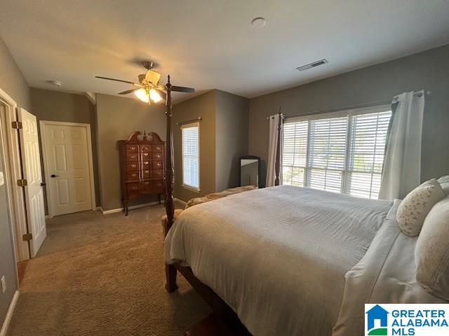 carpeted bedroom featuring a ceiling fan, visible vents, and baseboards