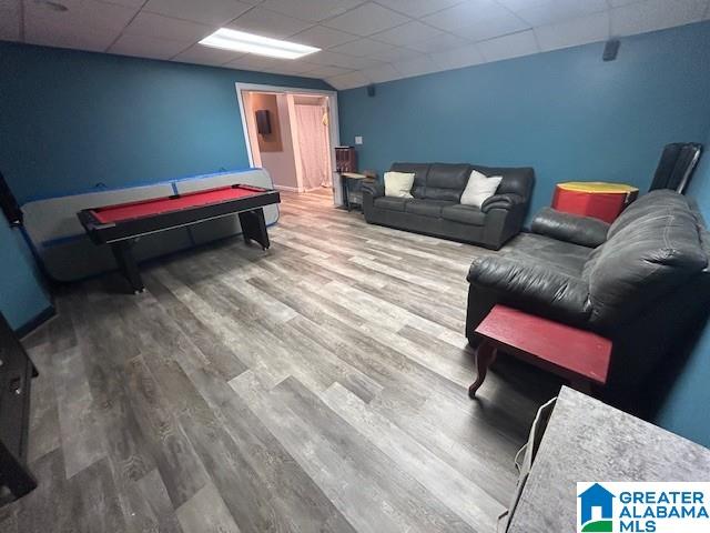 living area featuring a drop ceiling and wood finished floors