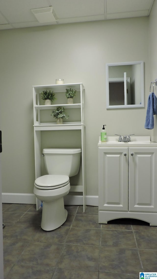 bathroom featuring baseboards, visible vents, toilet, vanity, and a paneled ceiling