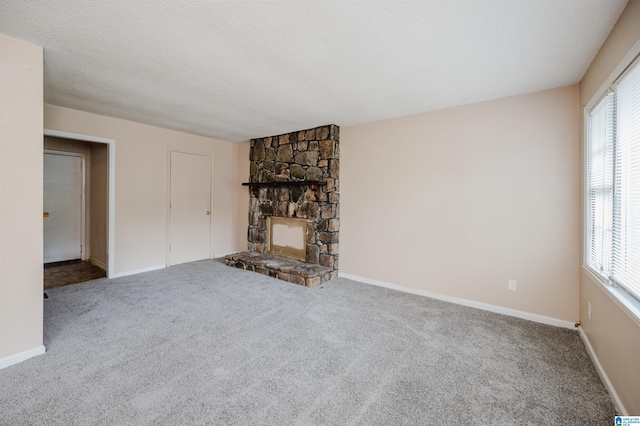 unfurnished living room with a textured ceiling, a fireplace, carpet flooring, and a wealth of natural light