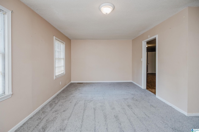 carpeted empty room featuring baseboards and a textured ceiling