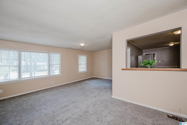 empty room with carpet, visible vents, a textured ceiling, and baseboards