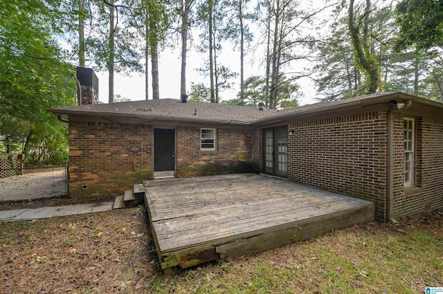 back of property featuring a chimney, a deck, and brick siding