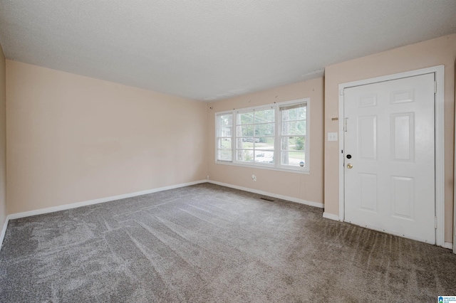 carpeted entrance foyer with a textured ceiling and baseboards