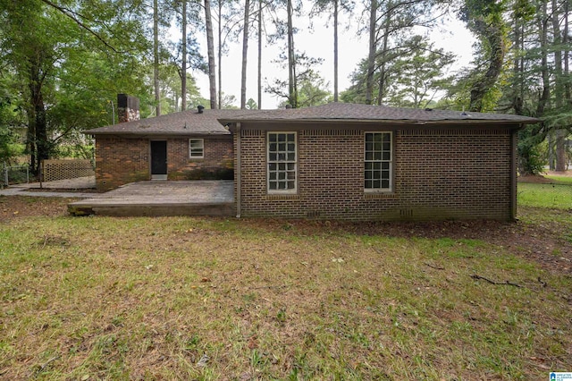 back of house with brick siding, a patio, a chimney, a lawn, and crawl space