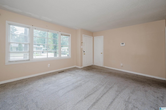 unfurnished room featuring carpet floors, visible vents, a textured ceiling, and baseboards