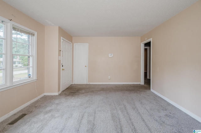 spare room featuring visible vents, a textured ceiling, and baseboards