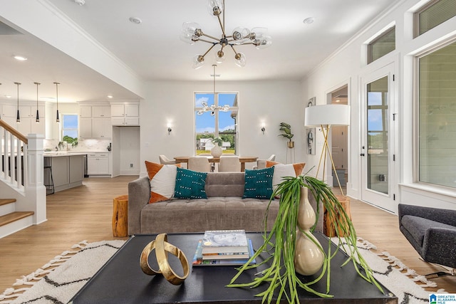 living room featuring an inviting chandelier, plenty of natural light, stairs, and crown molding