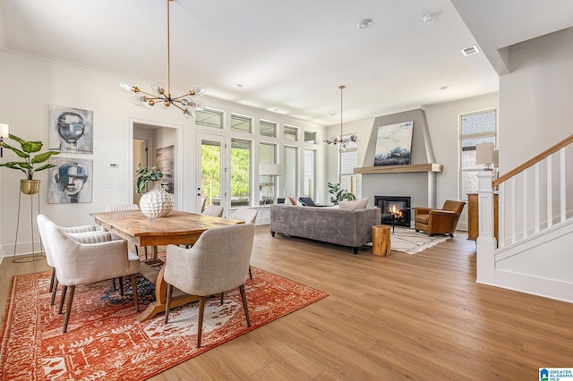 dining room with light wood finished floors, stairway, a wealth of natural light, and an inviting chandelier