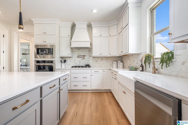 kitchen with light countertops, appliances with stainless steel finishes, custom exhaust hood, and white cabinets