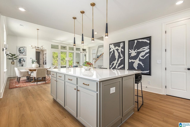 kitchen featuring a center island, pendant lighting, light countertops, gray cabinetry, and ornamental molding