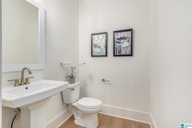 bathroom with a sink, wood finished floors, toilet, and baseboards