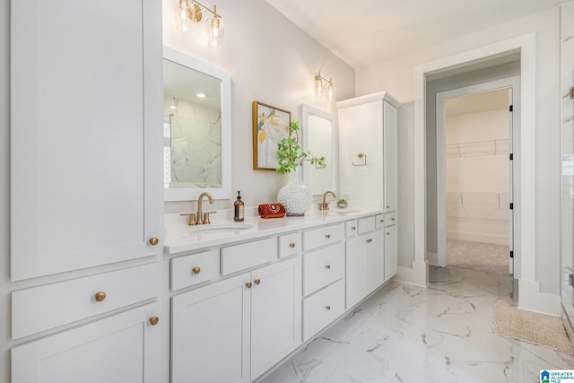 bathroom featuring marble finish floor, a sink, a spacious closet, and double vanity