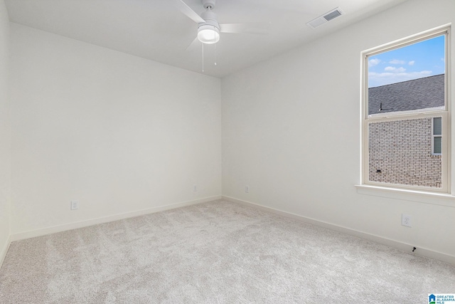 spare room with light carpet, baseboards, visible vents, and a ceiling fan