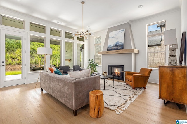 interior space with a notable chandelier, ornamental molding, a fireplace, and light wood-style floors