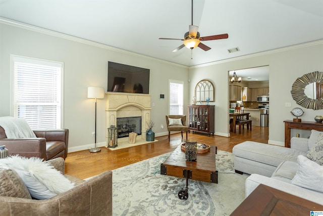 living area featuring a healthy amount of sunlight, a fireplace, visible vents, and crown molding