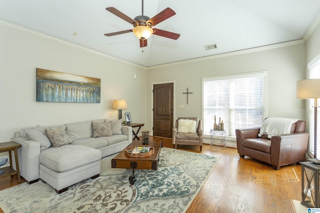 living area with visible vents, ornamental molding, vaulted ceiling, ceiling fan, and wood finished floors