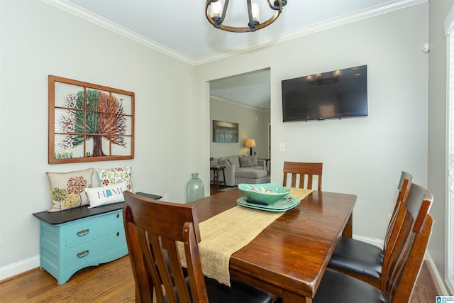 dining area with light wood finished floors, baseboards, ornamental molding, and a notable chandelier