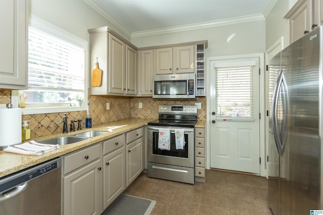 kitchen with appliances with stainless steel finishes, backsplash, a sink, and crown molding