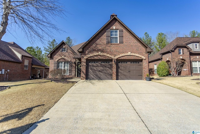 view of front facade with concrete driveway, brick siding, a chimney, and a front yard