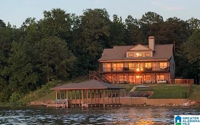 rear view of house with a water view, a lawn, and a wooded view