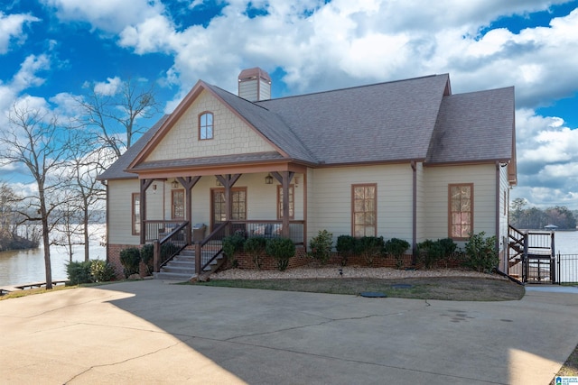 view of front of home featuring covered porch, a shingled roof, and a chimney