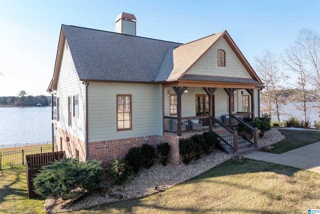 view of front of home featuring a porch, a chimney, a front lawn, and brick siding