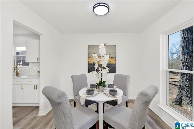 dining area featuring light wood-style flooring and baseboards