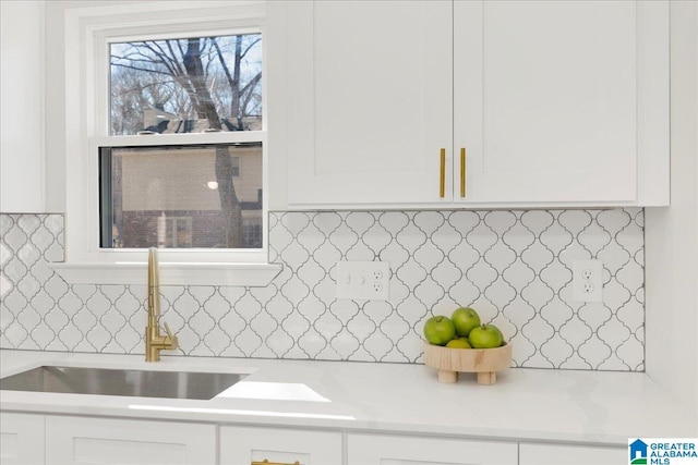 kitchen featuring white cabinets, a sink, and backsplash