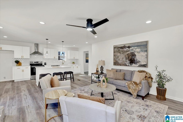 living room with baseboards, ceiling fan, recessed lighting, and light wood-style floors