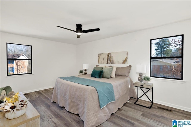 bedroom with dark wood-style floors, a ceiling fan, visible vents, and baseboards