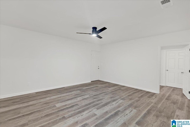 empty room with light wood-style floors, visible vents, baseboards, and a ceiling fan