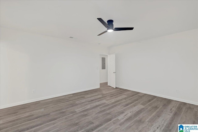 unfurnished room with light wood-style floors, electric panel, ceiling fan, and baseboards