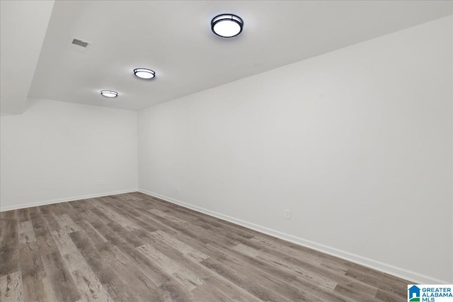 spare room featuring baseboards, visible vents, and wood finished floors