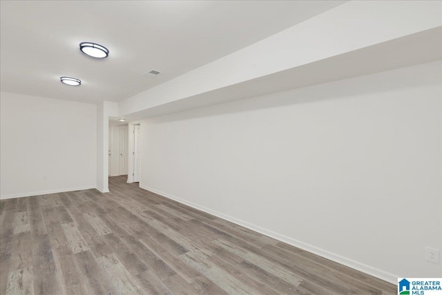 finished basement featuring light wood-style flooring, visible vents, and baseboards