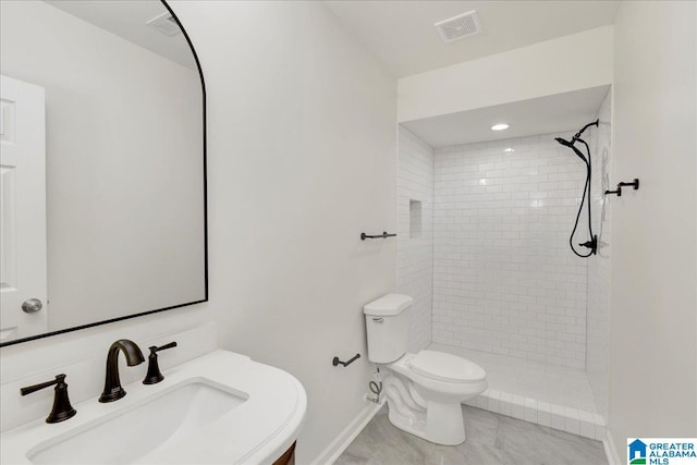 full bath featuring a tile shower, visible vents, a sink, and toilet