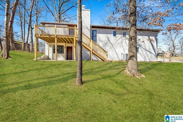 back of house featuring brick siding, a yard, a chimney, stairway, and a wooden deck