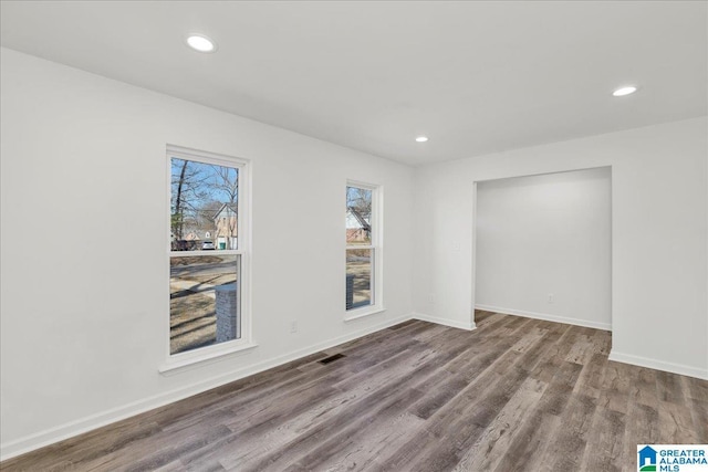 spare room with recessed lighting, visible vents, baseboards, and wood finished floors